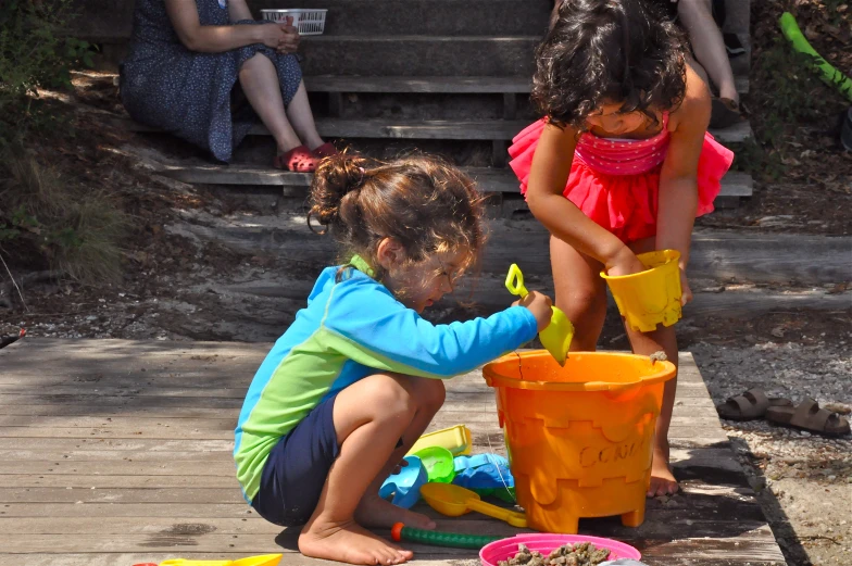 two little girls playing with a bucket and sand