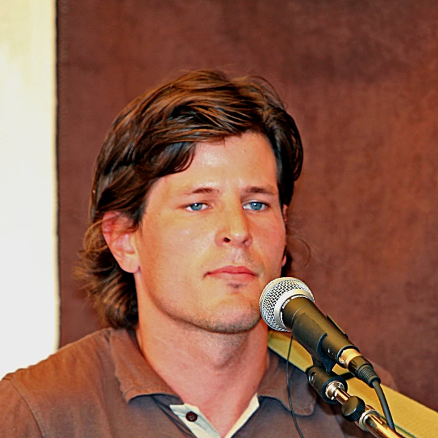 a man stands behind a microphone and looks up to the right