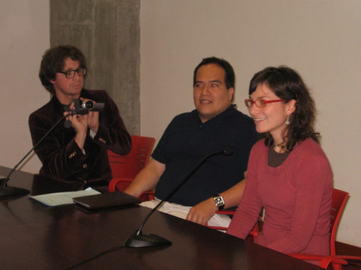 a woman holding a microphone standing in front of two men