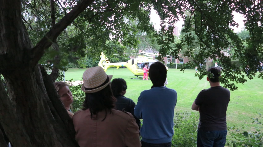 four people are standing around a tree looking at a helicopter