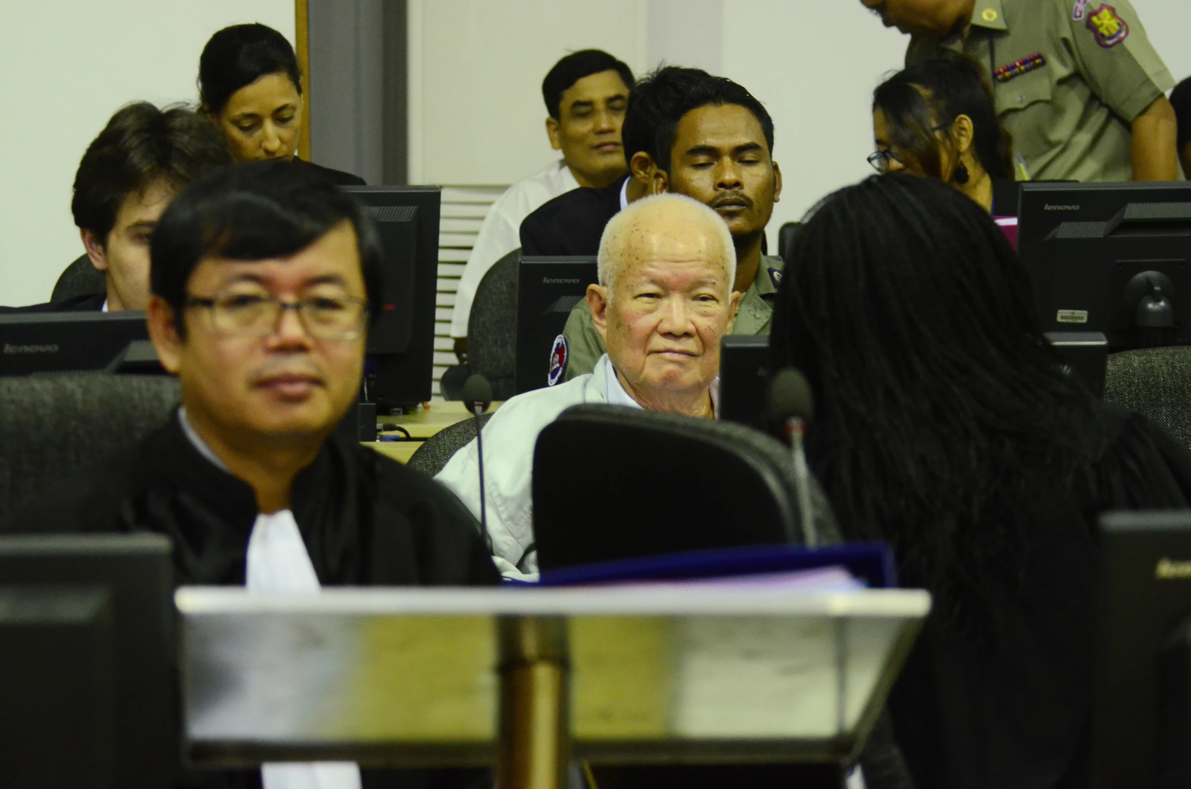 an older man in a courtroom with others behind him
