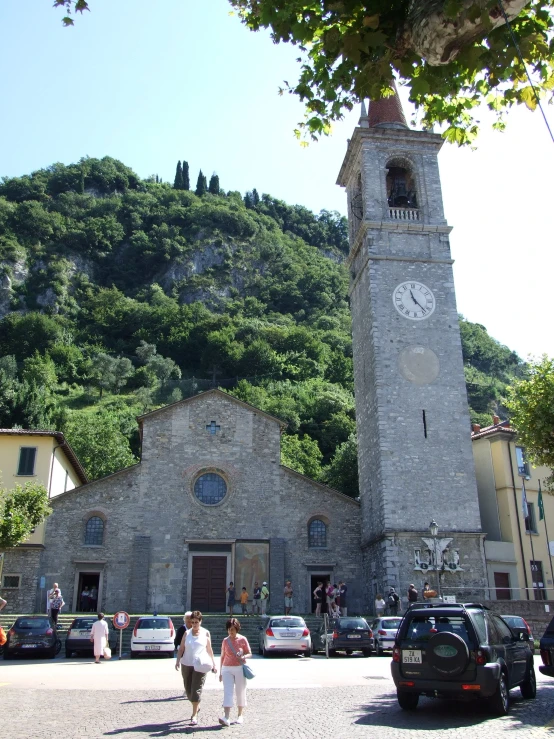 an old building with a clock tower, cars and people in the street