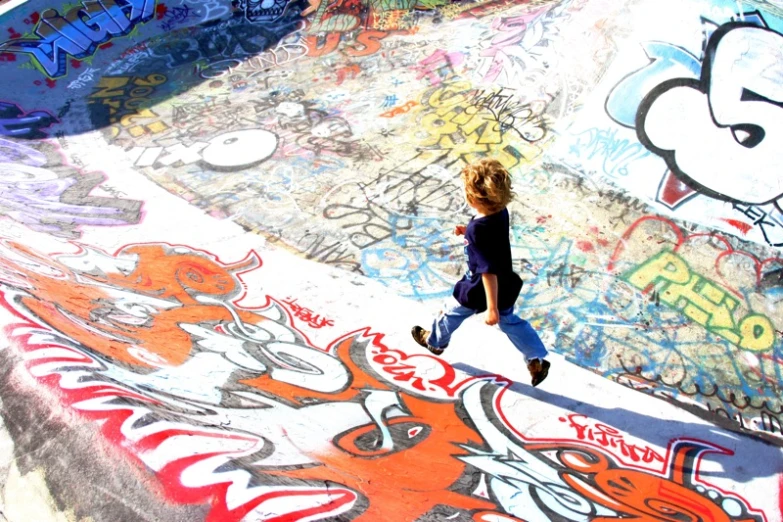 a boy rides down a skateboard ramp in front of graffiti