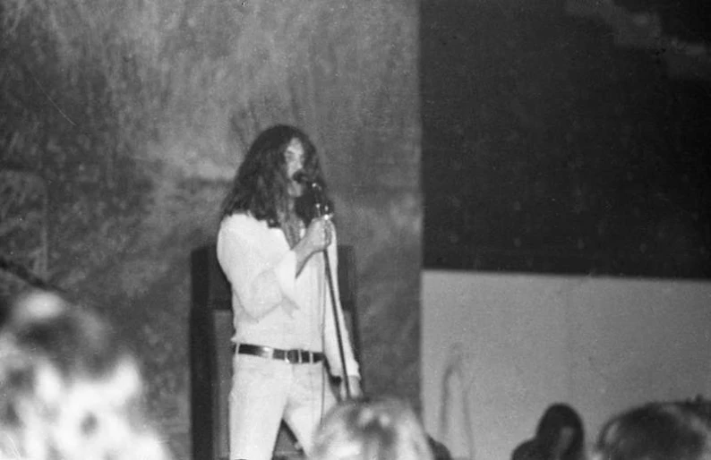 a man in a white suit singing into a microphone