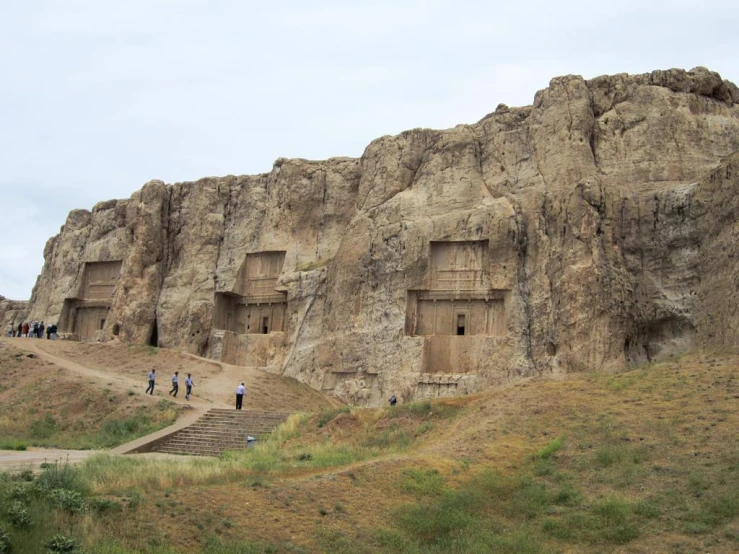 people walk in front of some strange stone structures