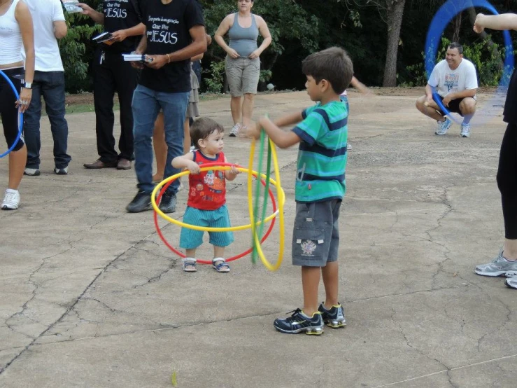 two boys play with some colorful rings while others watch