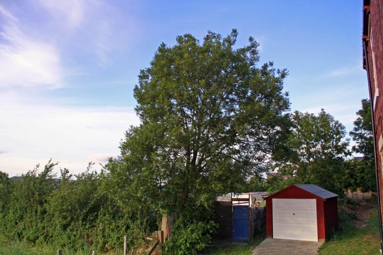 two garages with a red building and tree on the side