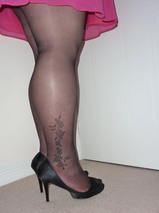 a woman in high heeled shoes with tattoos on her leg