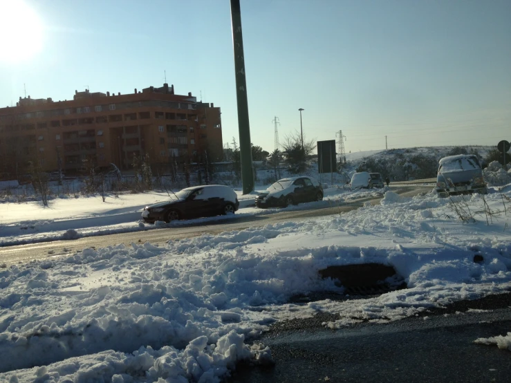 the snow is piled around parked cars near the curb