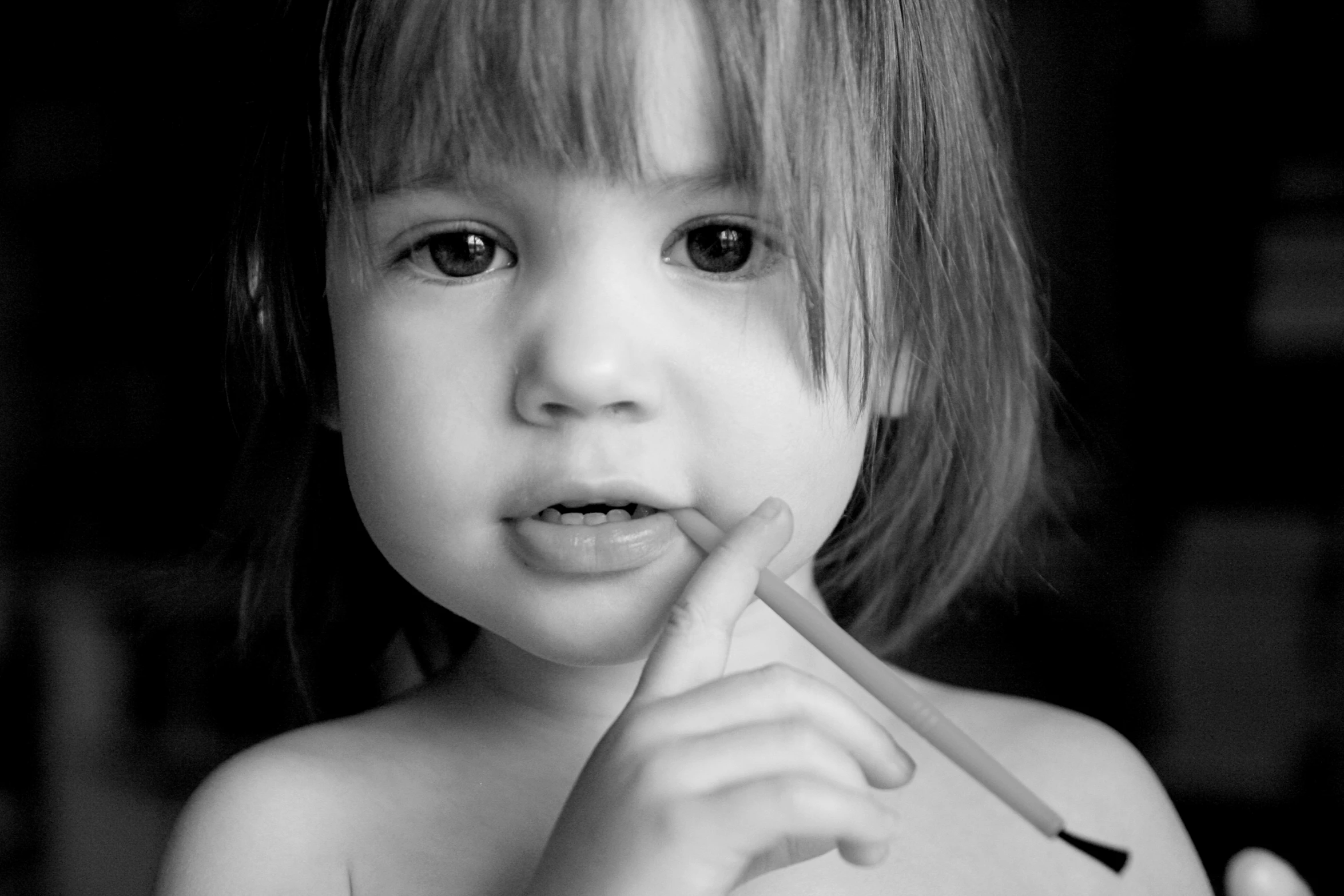 a black and white po of a little girl holding a pencil