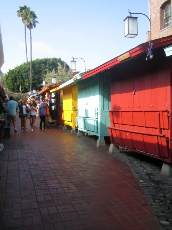 people walking around a brightly colored building on a brick road