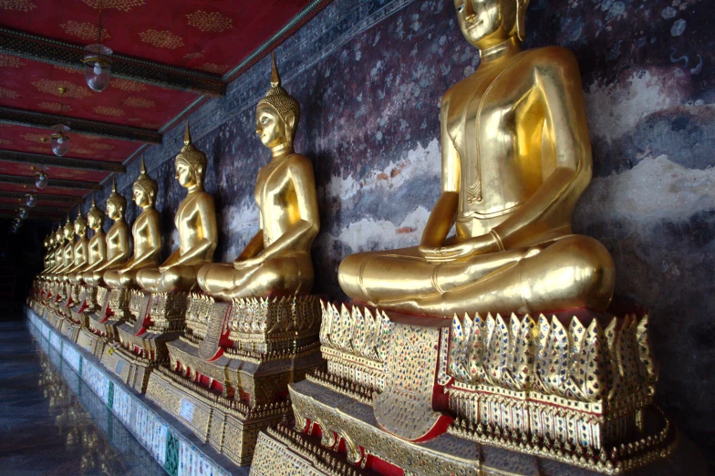 many gold buddhas sitting side by side in an area