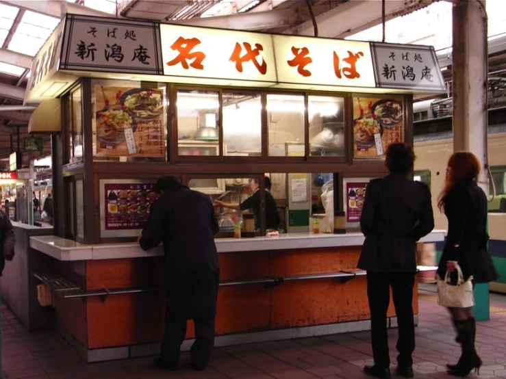 a group of people standing outside of a food stand