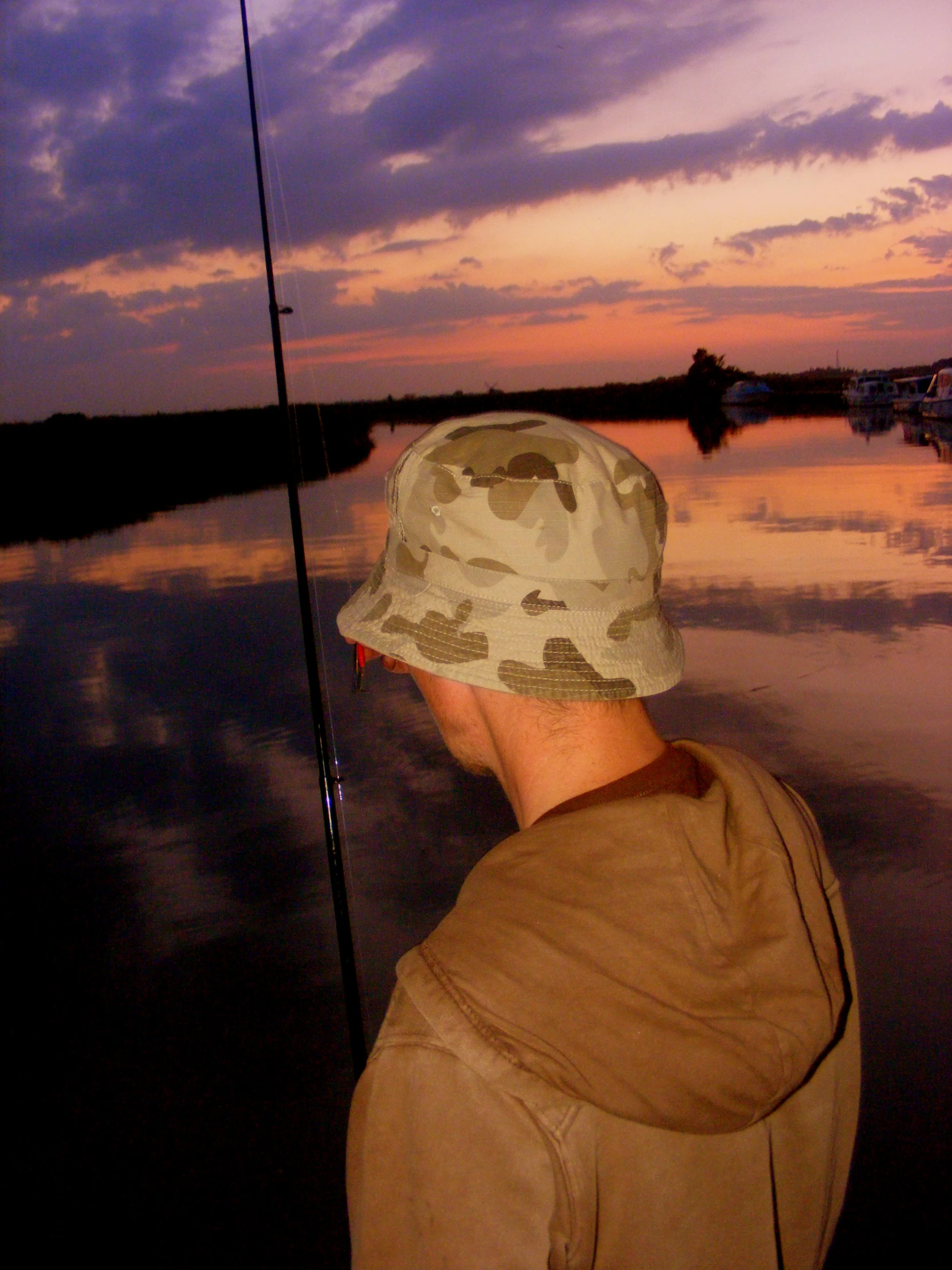 a man holding a fishing pole looking at the sky and water