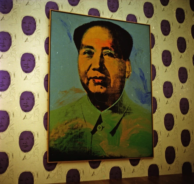 a painting of a picture of mao in gold and blue on a white wall with purple polka dots