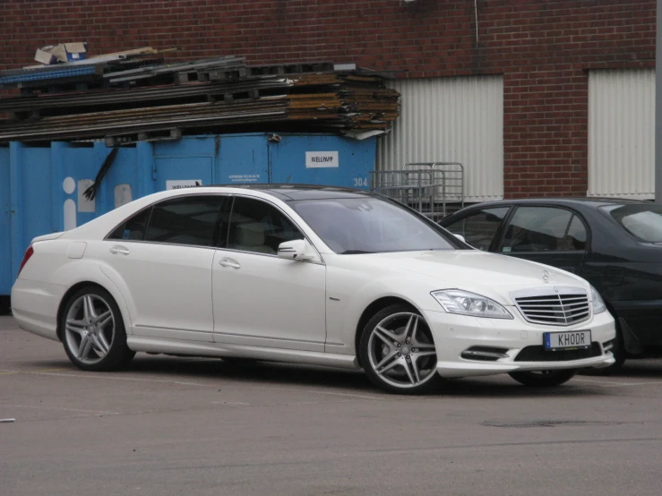 the white mercedes benz is parked in front of a dumpster