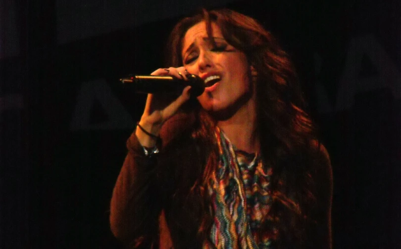 a woman sings into a microphone in the dark