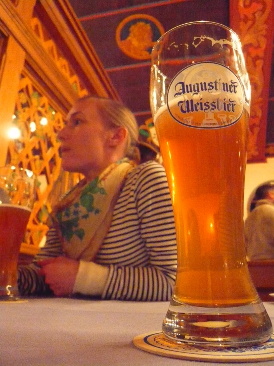 a glass of beer sits on a table in front of people
