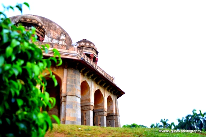 an old stone building sits on top of a green hillside