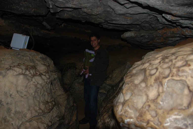 the man is standing in the cave holding flowers