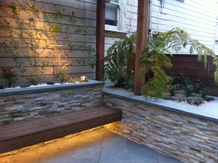 a wooden bench sitting next to a brick wall