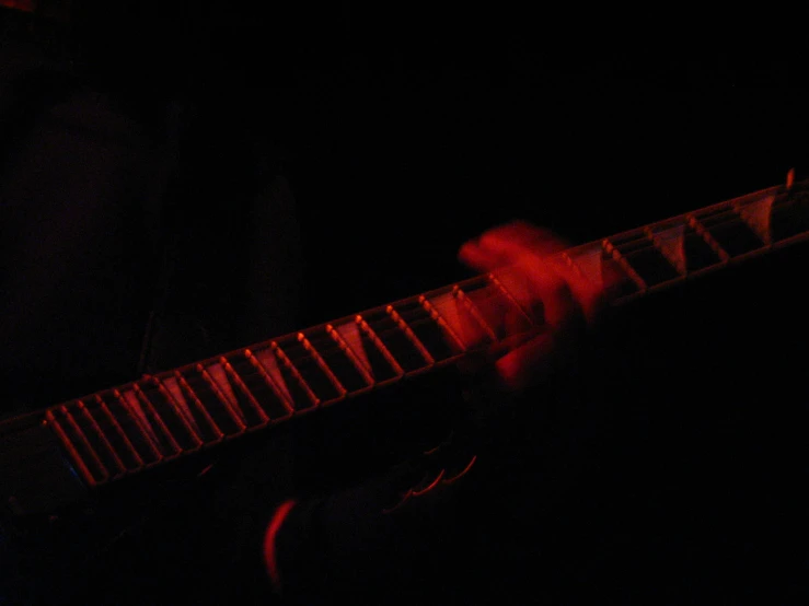 a man with red lighting plays a guitar in the dark