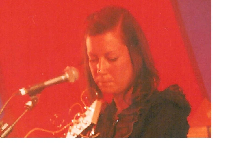 woman holding a guitar looking at the microphone