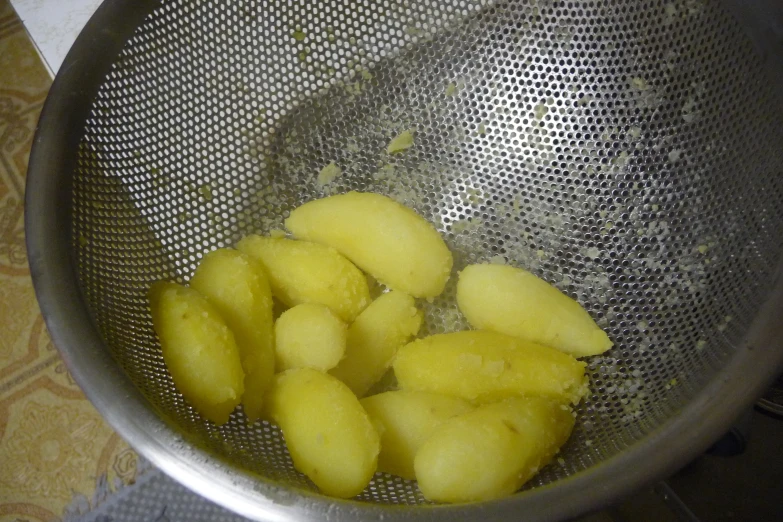 this is the inside of a strainer bowl containing chopped pineapple
