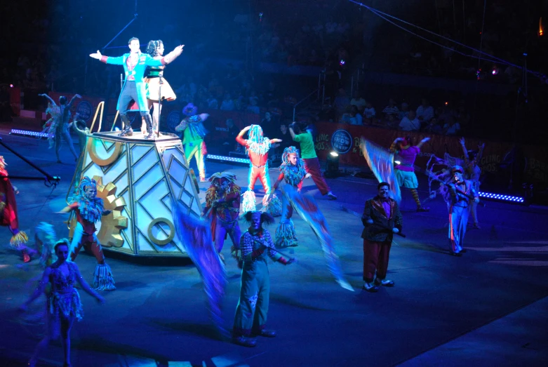 several circus performers with lights around them are standing on top of a drum