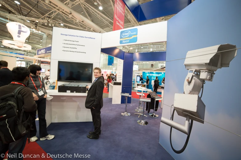 a man in a suit stands next to a display of a tv