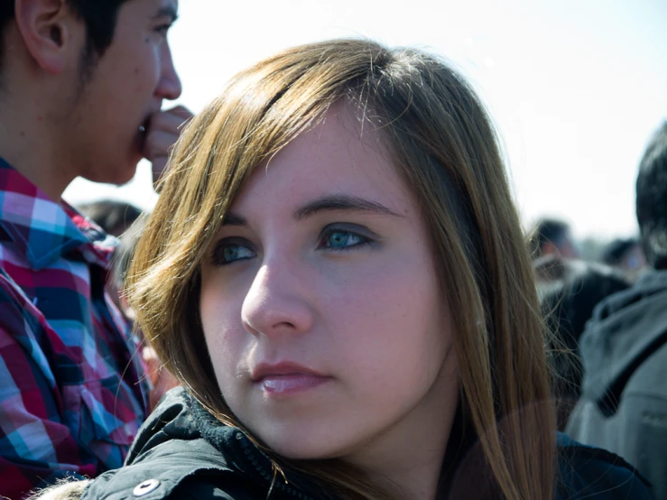 a woman looking out over the crowd as a man talks on his cellphone