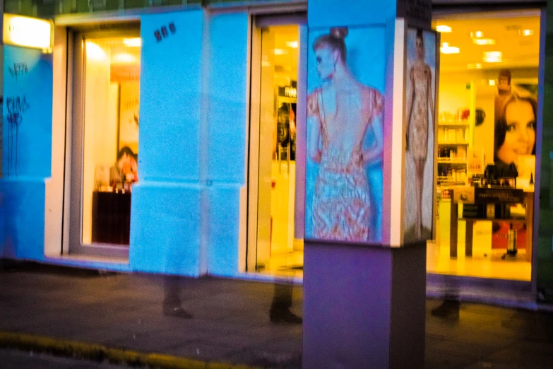 a store front with two lit up people and a building with graffiti