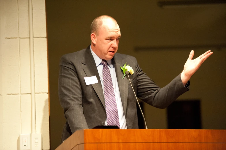 a man at a podium wearing a suit and tie