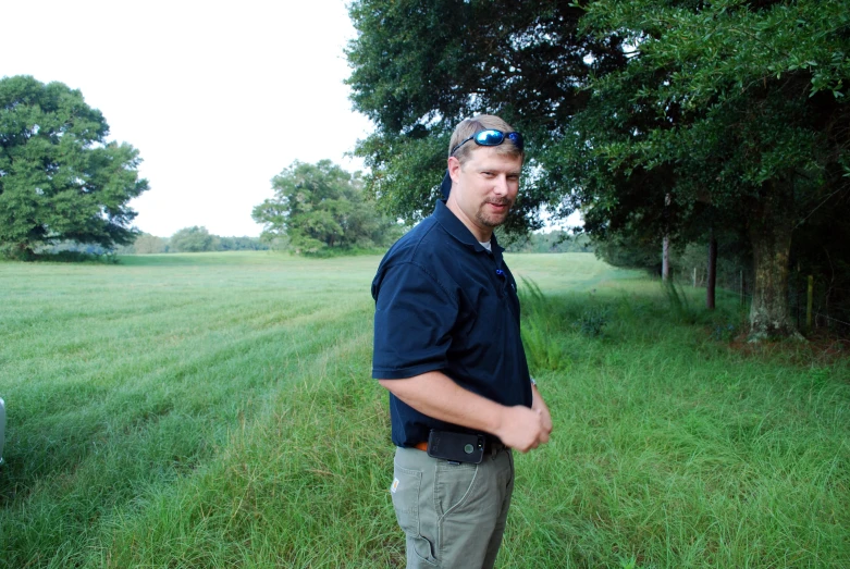 a man standing in a field with an object in the background