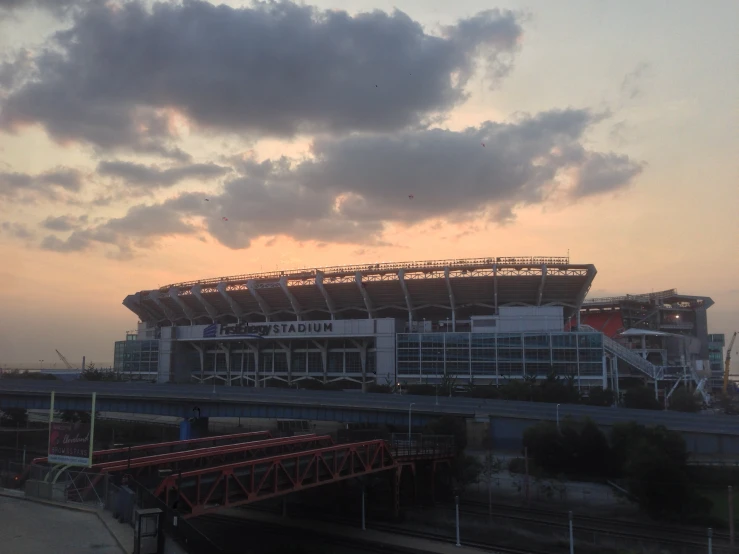 the sun sets behind a football stadium under a cloudy sky