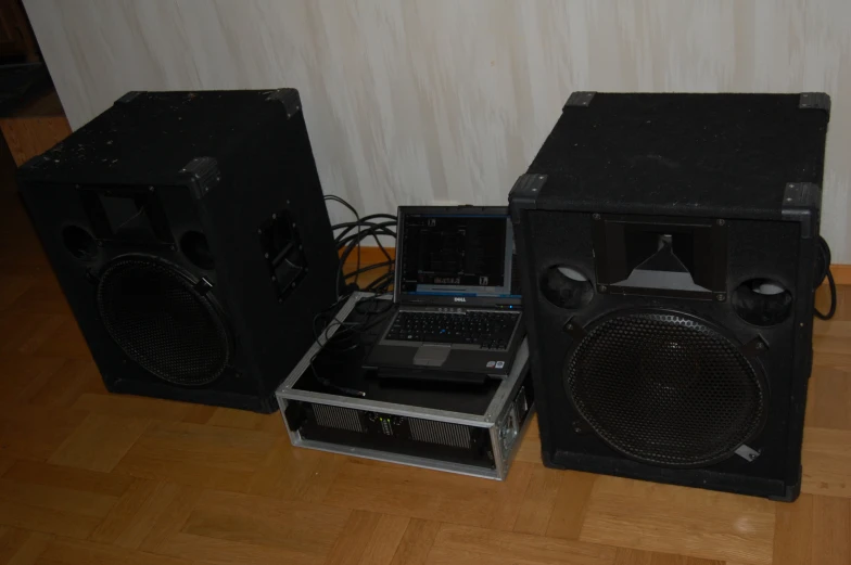 two speakers and a cd player sit on a hardwood floor