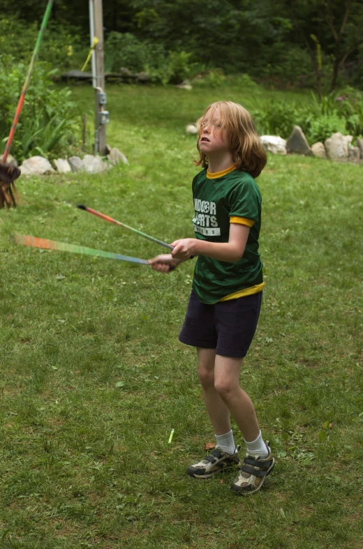 a little boy holding two green hoses