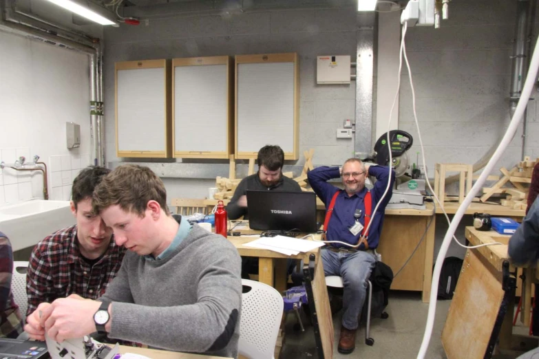 a group of men working on laptops in a garage