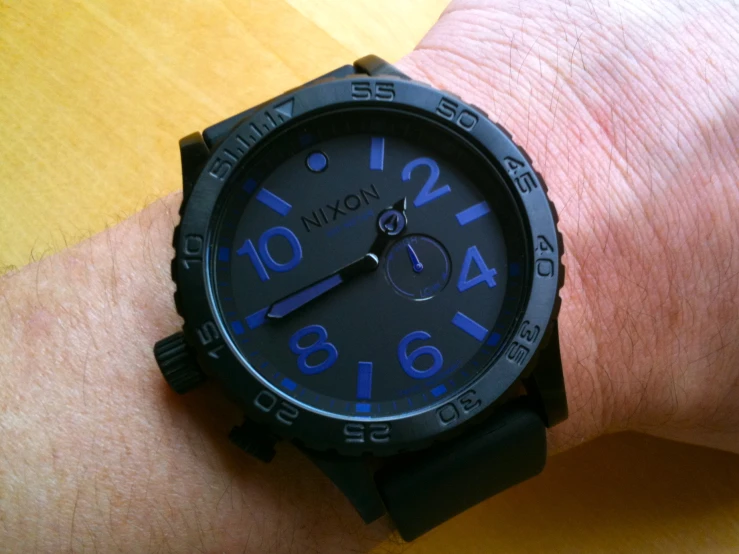 a wrist watch with black rubber bands and blue numbers