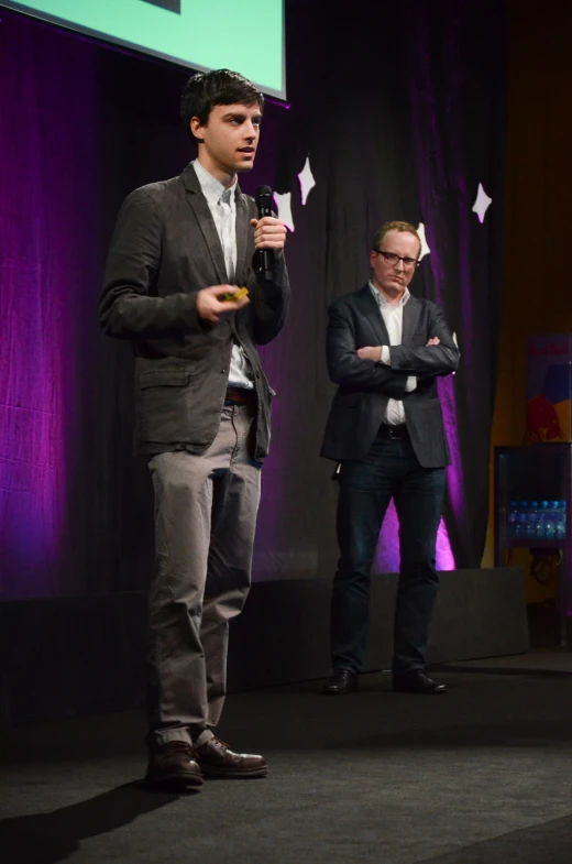 a man holding up two forks while standing in front of a man in a business suit