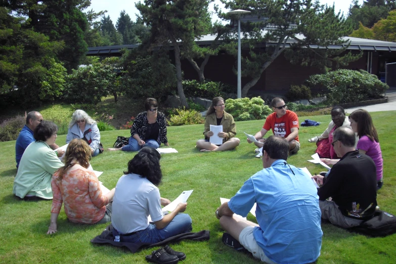 people sitting in the grass, all working on a project