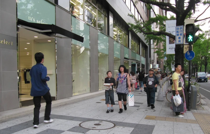 people are walking down a city street with a green light