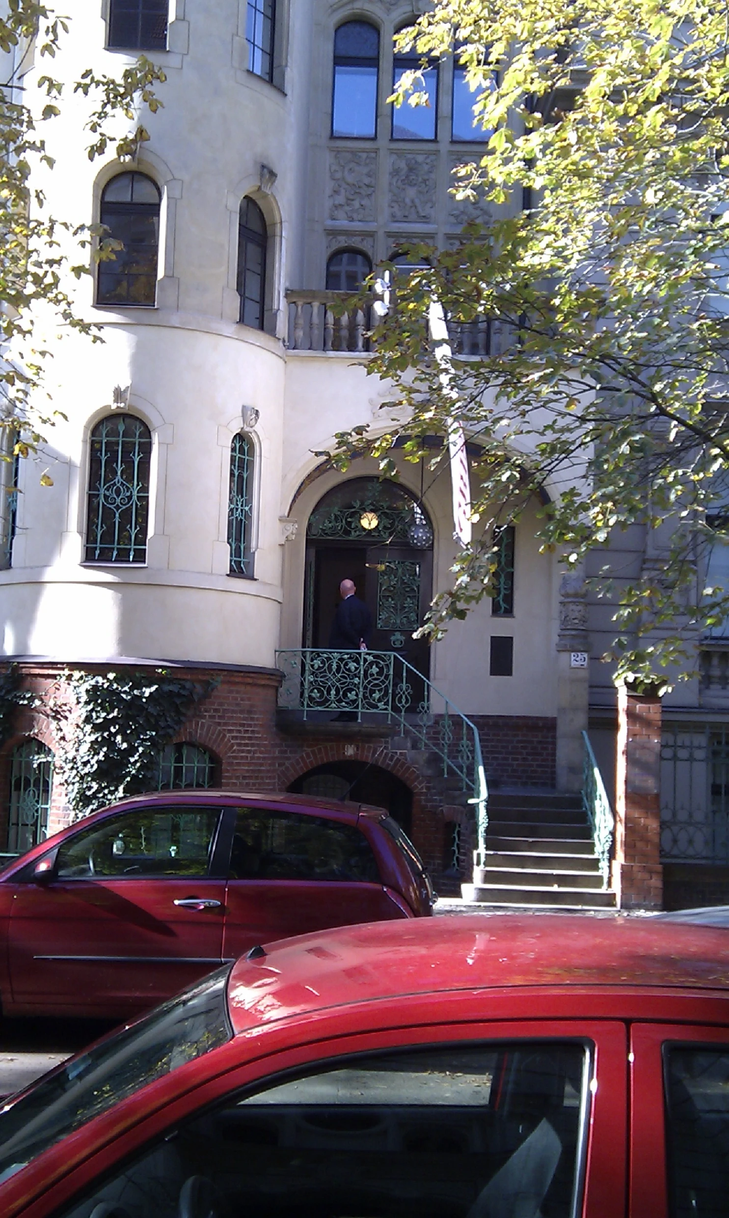 a red car parked next to a tall white building