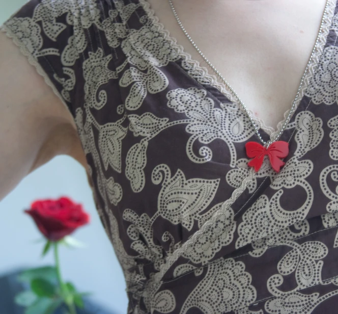 a person wearing a red necklace and a red rose