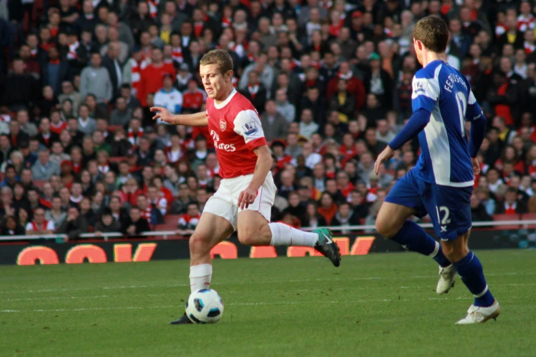 three players playing soccer in front of a full crowd