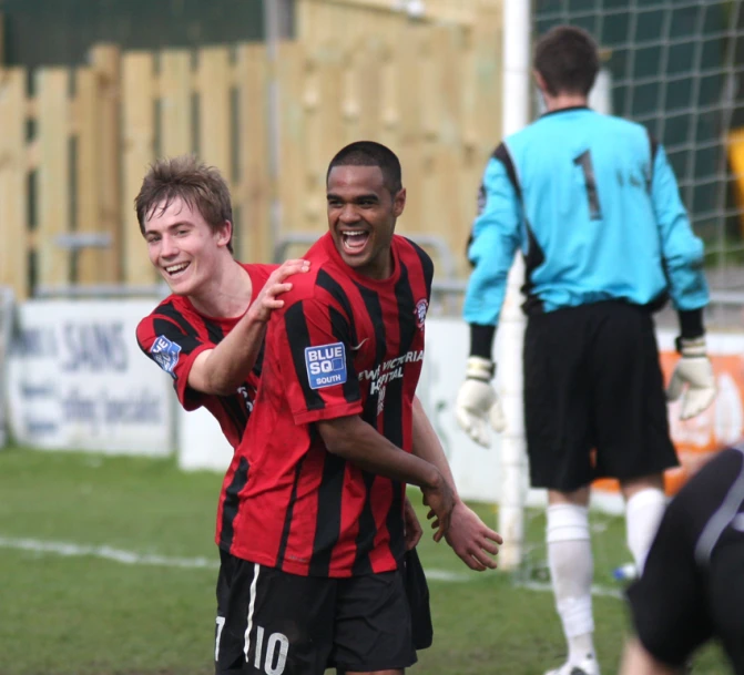 two men who are playing soccer in front of a net