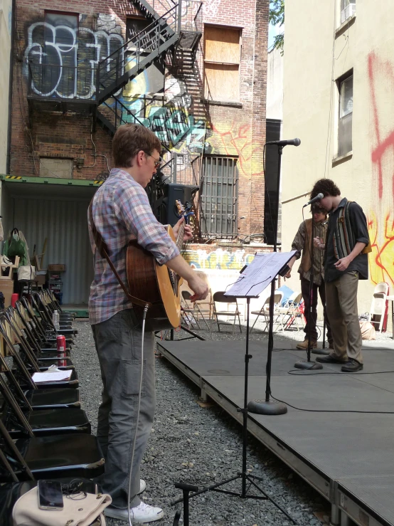 the two men are standing together while one is playing a guitar