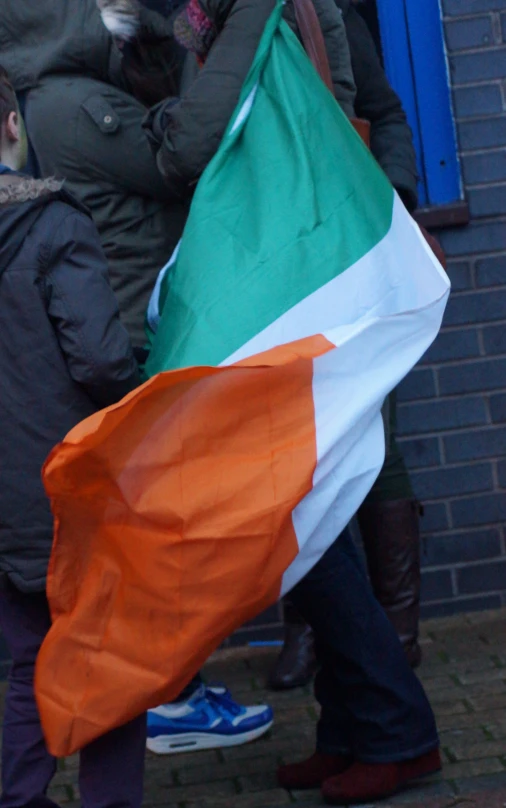 people are holding an orange, green, and white flag