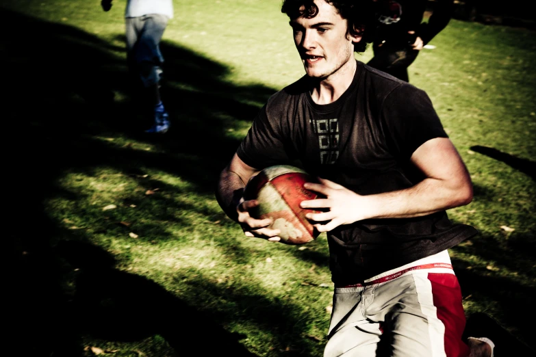 young man running with football in grassy field