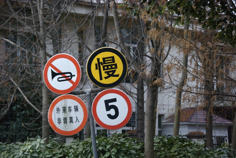 four different signs are placed in front of trees and plants